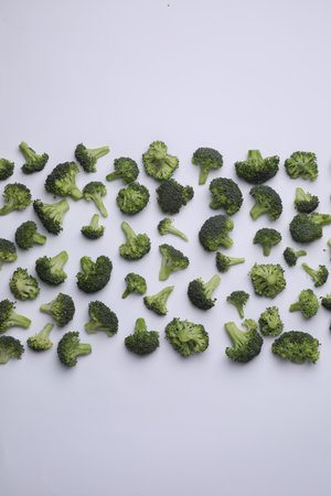 Many fresh green broccoli pieces on white background, flat layの写真素材