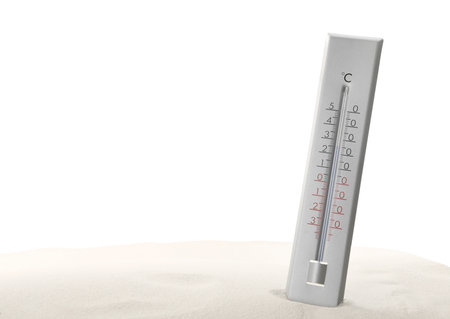 Weather thermometer in sand against white backgroundの写真素材