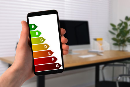 Energy efficiency. Man using smartphone with colorful rating on display indoors, closeupの写真素材