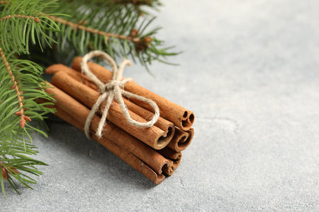 Bunch of cinnamon sticks and fir branches on gray textured table, closeup. Space for textの写真素材