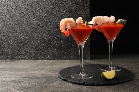 Tasty shrimp cocktail with sauce in glasses and lime on gray textured table, space for textの写真素材