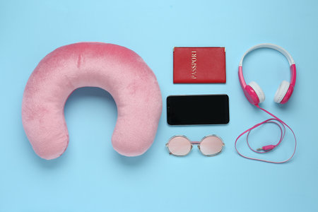 Flat lay composition with pink travel pillow and smartphone on light blue backgroundの写真素材
