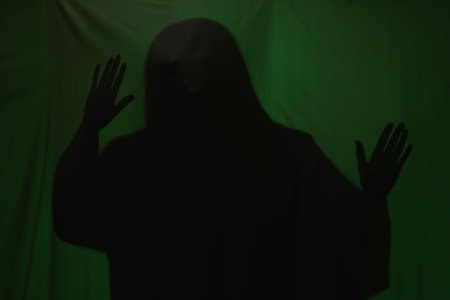 Silhouette of creepy ghost behind dark green clothの写真素材
