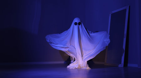 Creepy ghost. Woman covered with sheet in blue light, space for textの写真素材