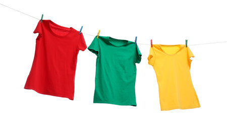 Different bright t-shirts drying on washing line against white backgroundの写真素材
