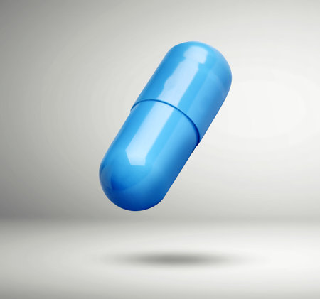 Light blue vitamin capsule in air on light gray backgroundの写真素材