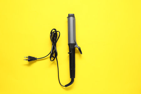 Curling iron on yellow background, top viewの写真素材