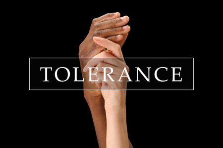 Tolerance, support and cooperation concept. Woman and man of different races holding hands on black...