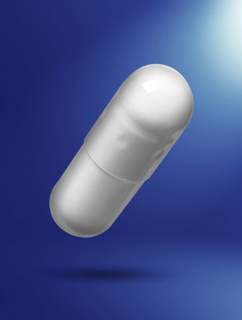 Vitamin capsule in air on blue gradient backgroundの写真素材