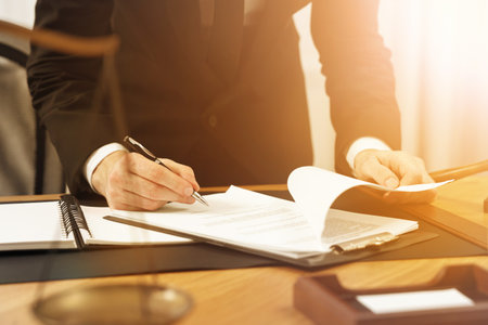 Lawyer working with documents at wooden table in office, closeup