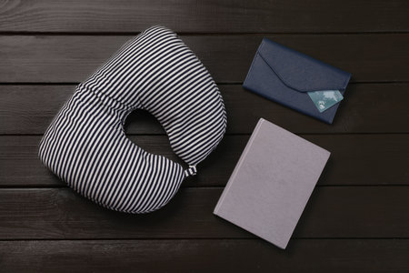 Striped travel pillow, notebook and wallet with credit card on dark wooden background, flat layの写真素材