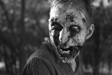Scary zombie outdoors, black and white effect. Halloween monster