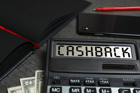 Calculator with word Cashback, money, phone and notebook on dark table, closeupの写真素材