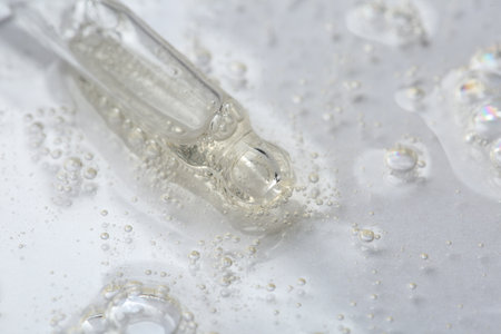 Pipette with cosmetic serum on white background, macro view. Space for text