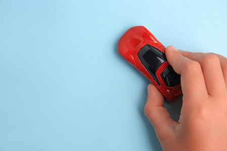 Child playing with toy car on light blue background, top view. Space for textの写真素材