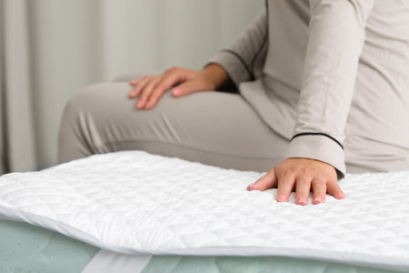 Woman sitting on new soft mattress indoors, closeupの写真素材