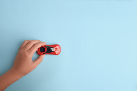 Child playing with toy car on light blue background, top view. Space for textの写真素材