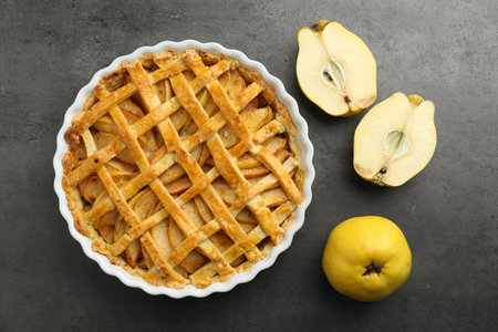 Tasty homemade quince pie and fresh fruits on gray table, flat layの写真素材