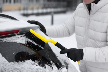 Man cleaning snow from car window outdoors, closeup