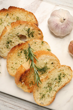 Tasty baguette with garlic, dill and rosemary on white wooden table, top viewの写真素材