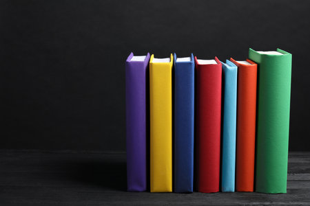 Different books on gray wooden table against dark background, space for textの写真素材