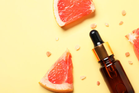 Flat lay composition with grapefruit essential oil on pale yellow background. Space for textの写真素材