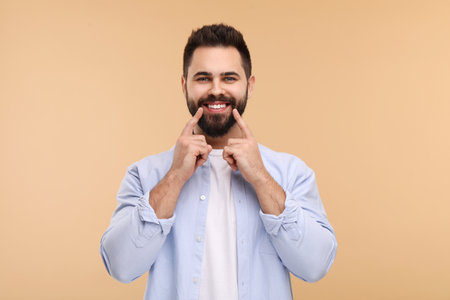Man showing his clean teeth and smiling on beige backgroundの写真素材