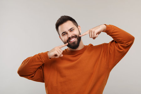 Man showing his clean teeth and smiling on gray background