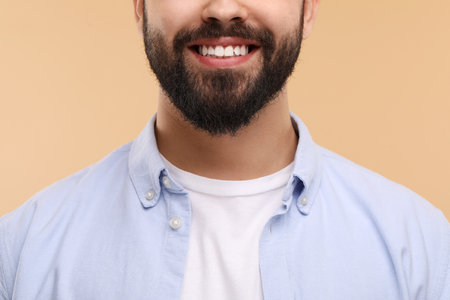 Man with clean teeth smiling on beige background, closeupの写真素材