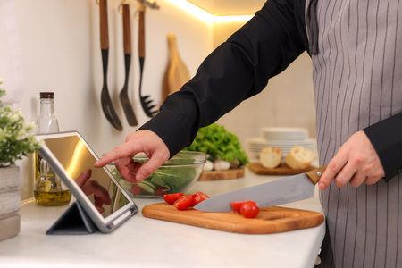 Man using tablet while cooking at countertop in kitchen, closeupの写真素材