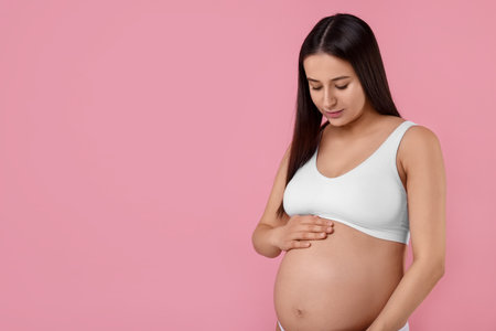 Beautiful pregnant woman in stylish comfortable underwear on pink background, space for textの写真素材
