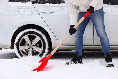 Man removing snow with shovel near car outdoors, closeupの写真素材