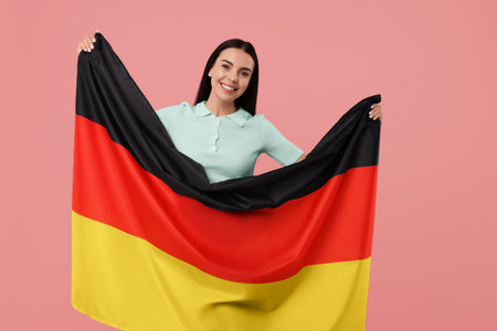 Happy young woman with flag of Germany on pink backgroundの写真素材