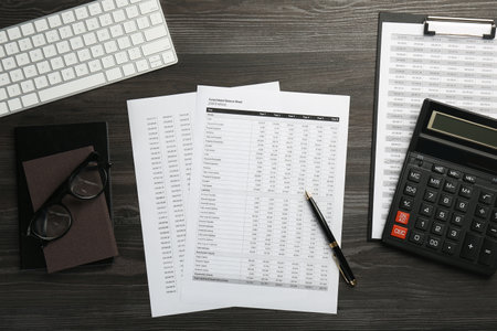 Accounting documents, glasses, stationery and computer keyboard on wooden table, flat layの写真素材