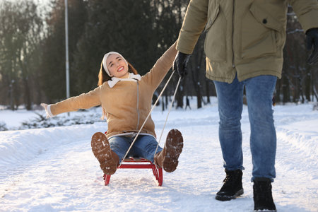 Man pulling his girlfriend in sleigh outdoors on winter dayの写真素材