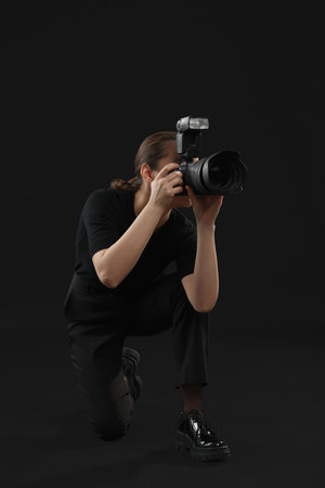 Professional photographer taking picture on black backgroundの写真素材