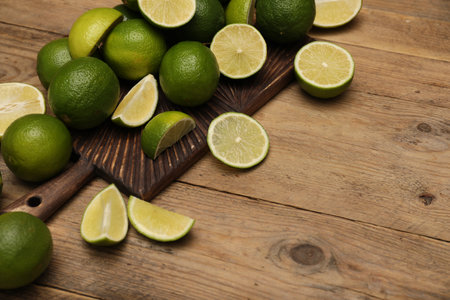 Fresh whole and cut limes on wooden table. Space for textの写真素材