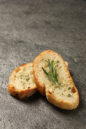 Tasty baguette with garlic, rosemary and dill on gray textured tableの写真素材