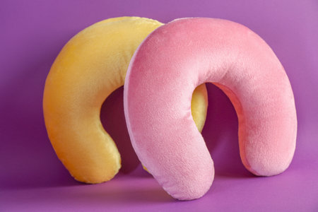 Pink and yellow travel pillows on violet backgroundの写真素材