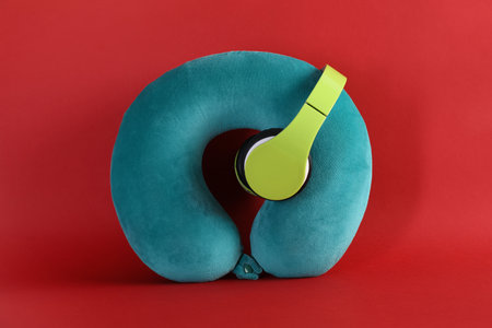 Turquoise travel pillow and headphones on red backgroundの写真素材