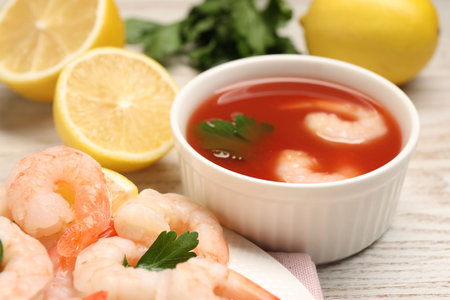 Tasty boiled shrimps with sauce cocktail, chili and parsley on light wooden table, closeupの写真素材
