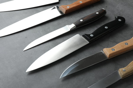 Many different knives on gray textured table