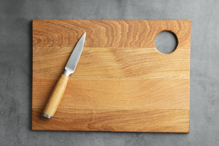 Knife and wooden board on gray textured table, top viewの写真素材