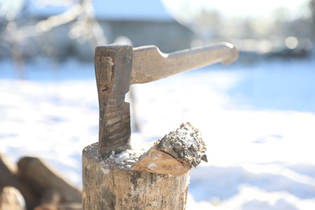 Metal ax in wooden log on sunny winter day, closeupの写真素材