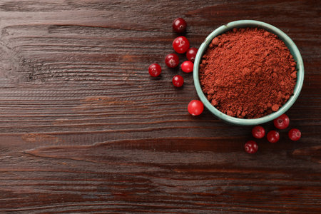 Dried cranberry powder in bowl and fresh berries on wooden table, top view. Space for textの写真素材