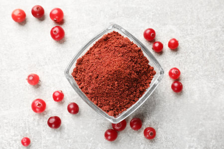 Cranberry powder in bowl and fresh berries on light gray table, top viewの写真素材