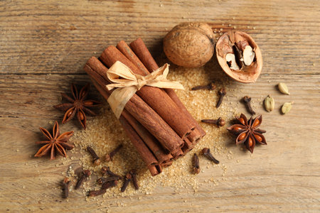 Different spices and nuts on wooden table, flat lay