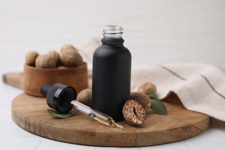 Nutmeg essential oil and nuts on white tableの写真素材