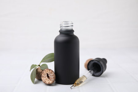 Nutmeg essential oil and nuts on white table