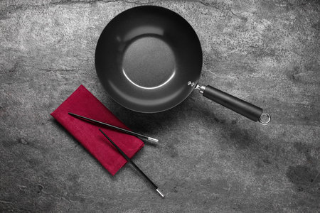 Empty iron wok and chopsticks on gray table, flat layの写真素材
